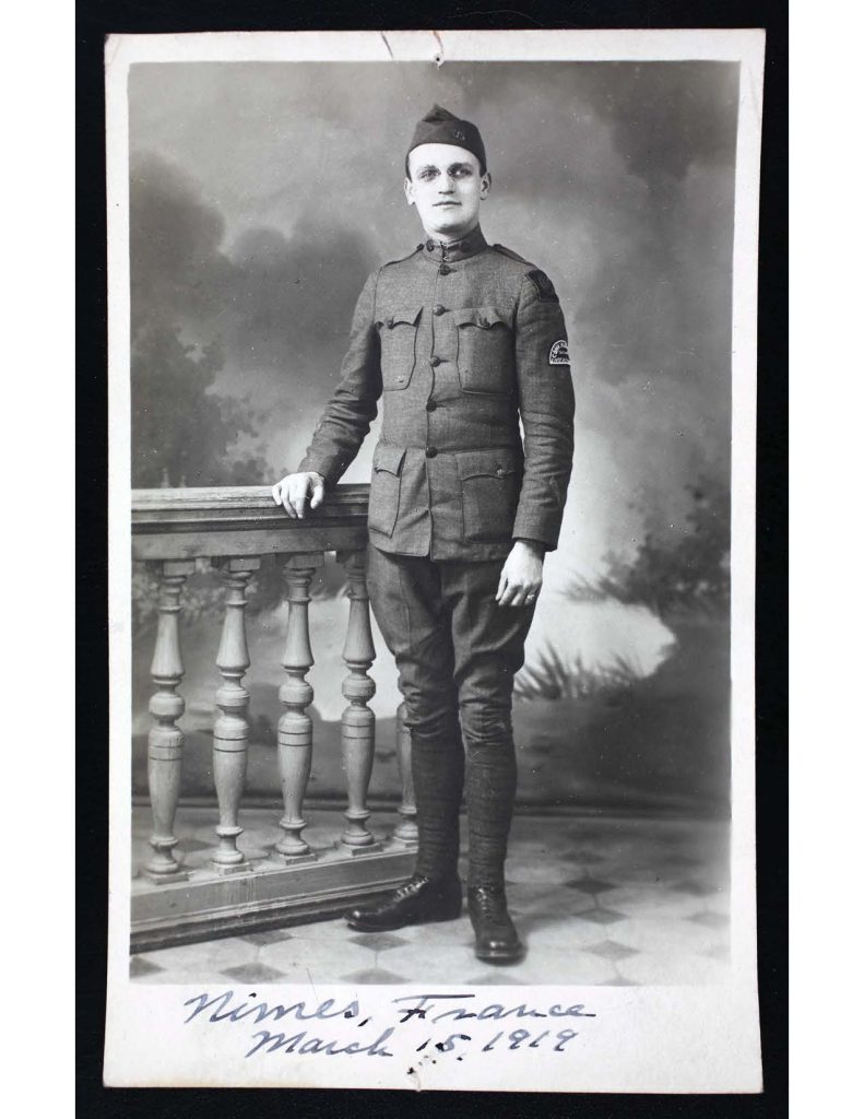a photo of lawrence thomas hager in military uniform standing in front of a gate, the photo was taken in nimes, france on march 15, 1919