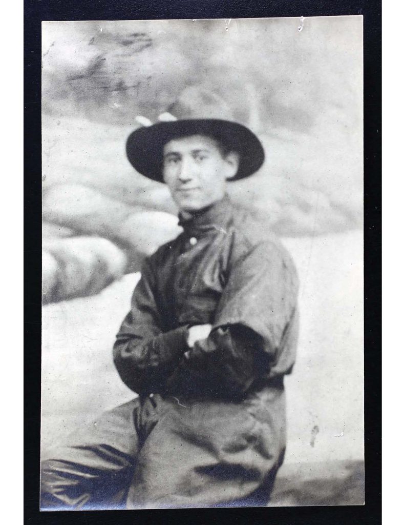 a black and white photo of solomon wollman wearing his military hat and uniform, he is sitting with his arms crossed