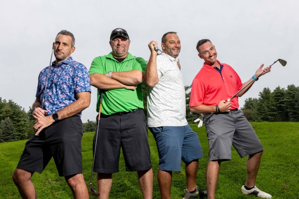 four men wearing colorful shirts, standing on a golf course